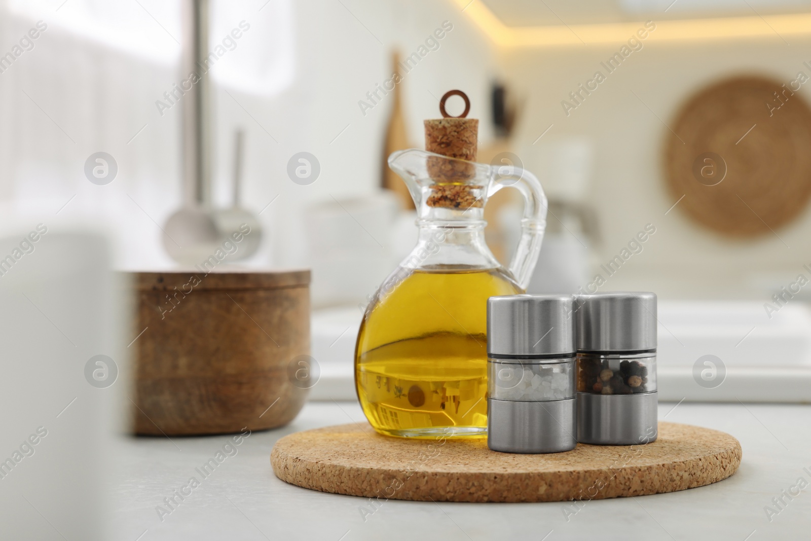 Photo of Salt and pepper mills with bottle of oil on table in kitchen