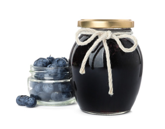 Jar of blueberry jam and fresh berries on white background