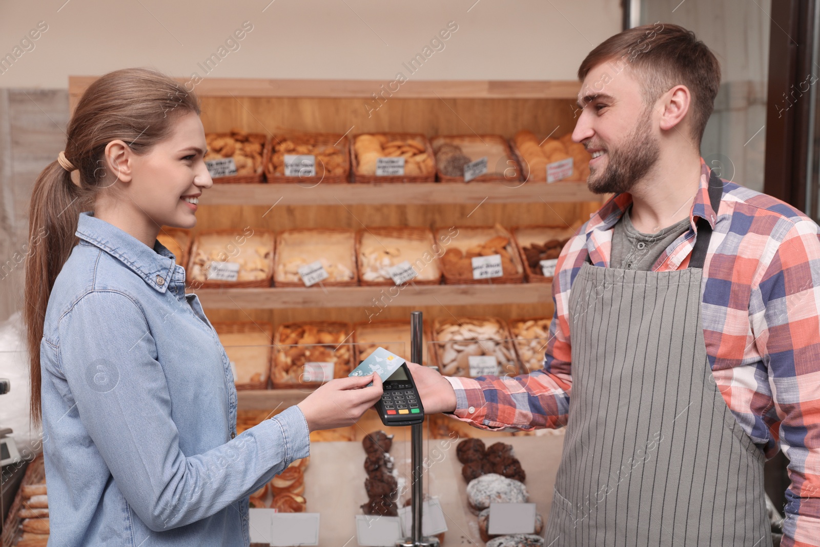 Photo of Woman using credit card for terminal payment in bakery