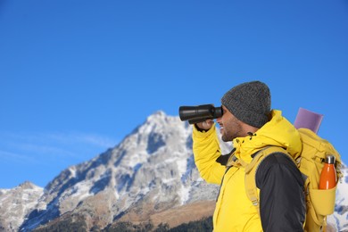Image of Tourist with backpack and binoculars in mountains