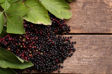 Photo of Pile of tasty elderberries (Sambucus) on wooden table, top view. Space for text