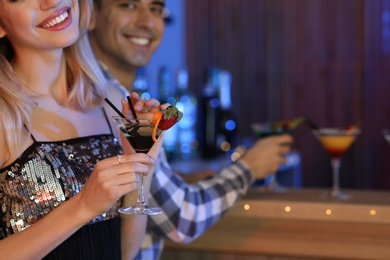 Photo of Young woman with glass of martini cocktail in bar, closeup. Space for text
