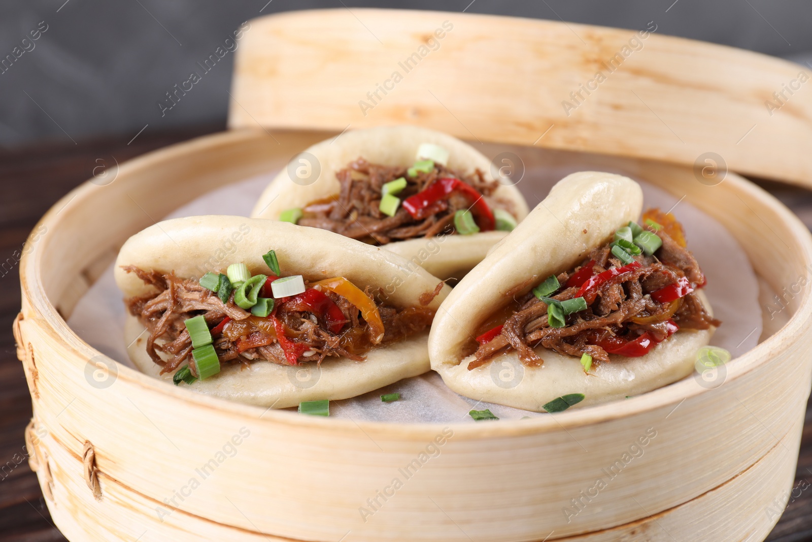 Photo of Delicious gua bao (pork belly buns) in bamboo steamer on table, closeup