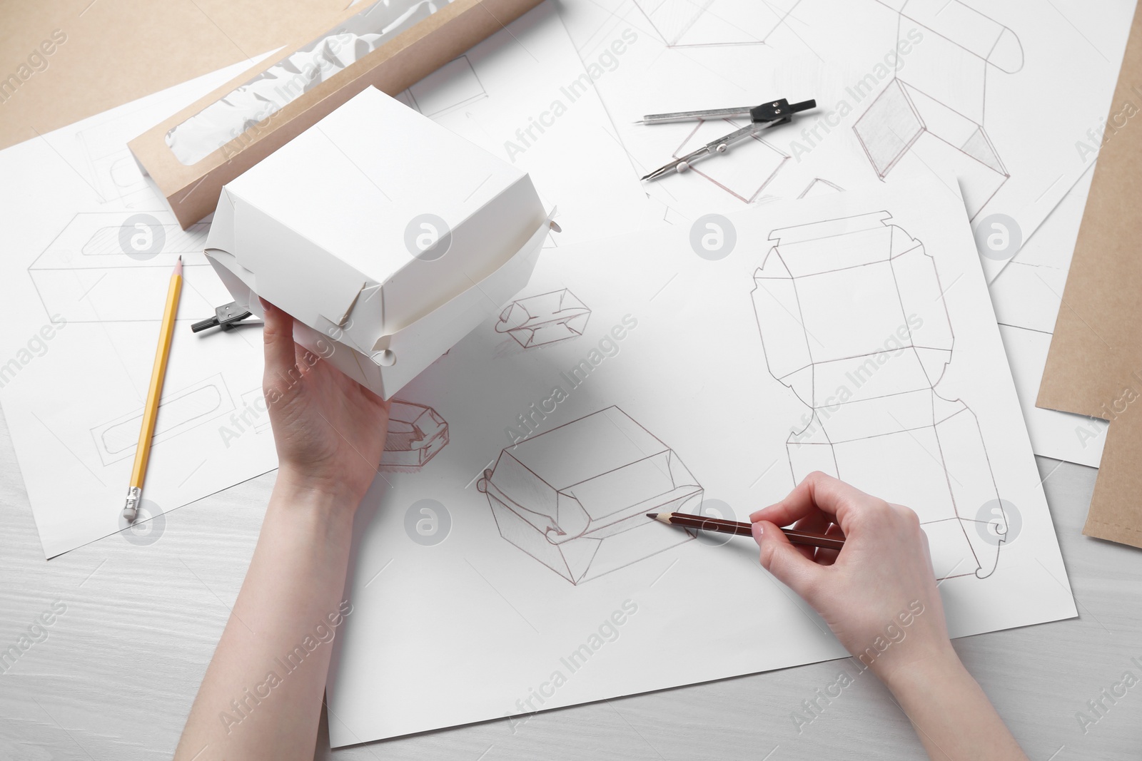 Photo of Woman creating packaging design at light wooden table, above view