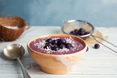 Bowl with tasty acai smoothie on wooden table