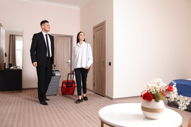 Photo of Happy businesspeople with suitcases walking into hotel room