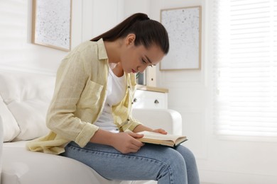 Photo of Young woman with poor posture reading book at home