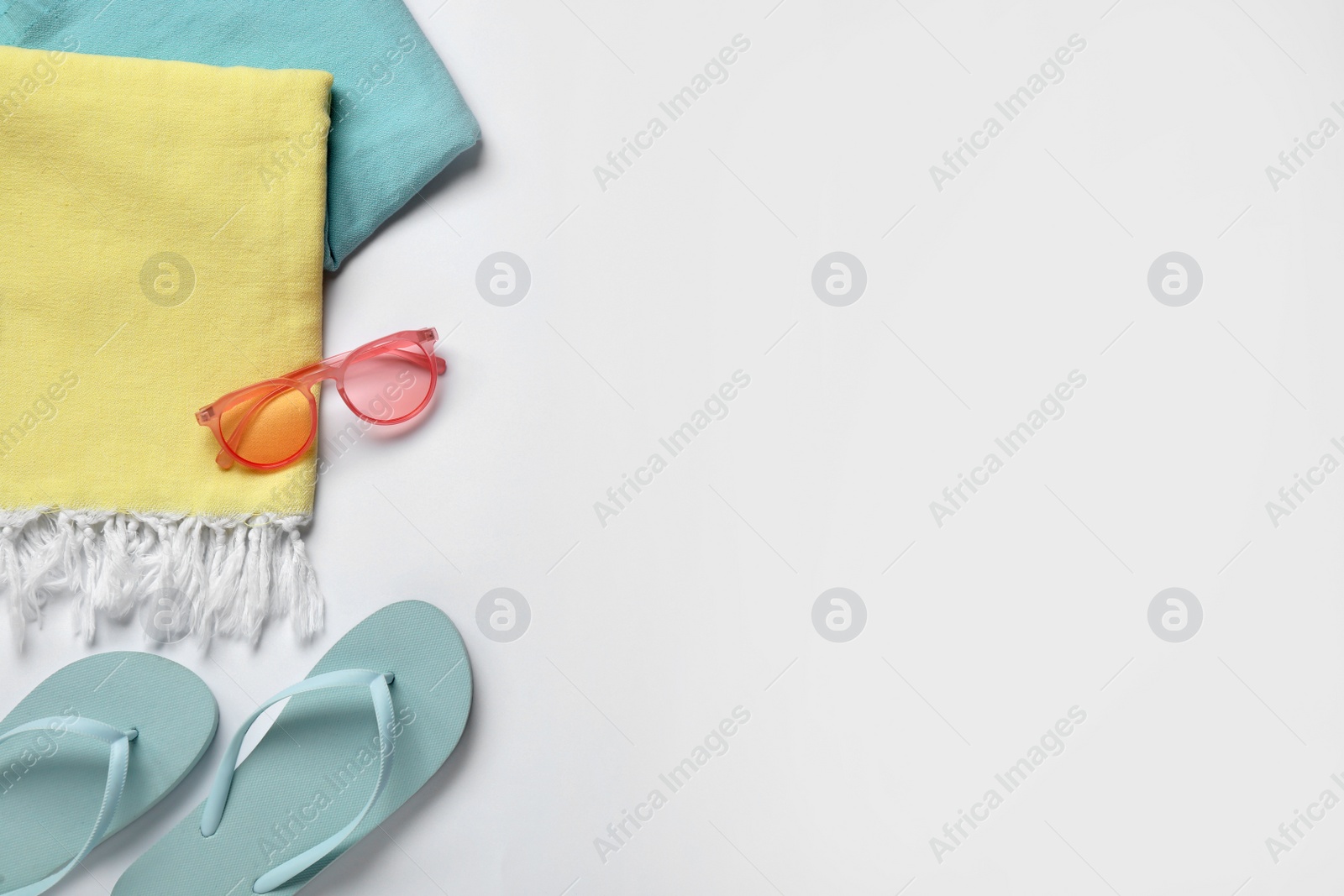 Photo of Beach towel, flip flops and sunglasses on white background, flat lay. Space for text