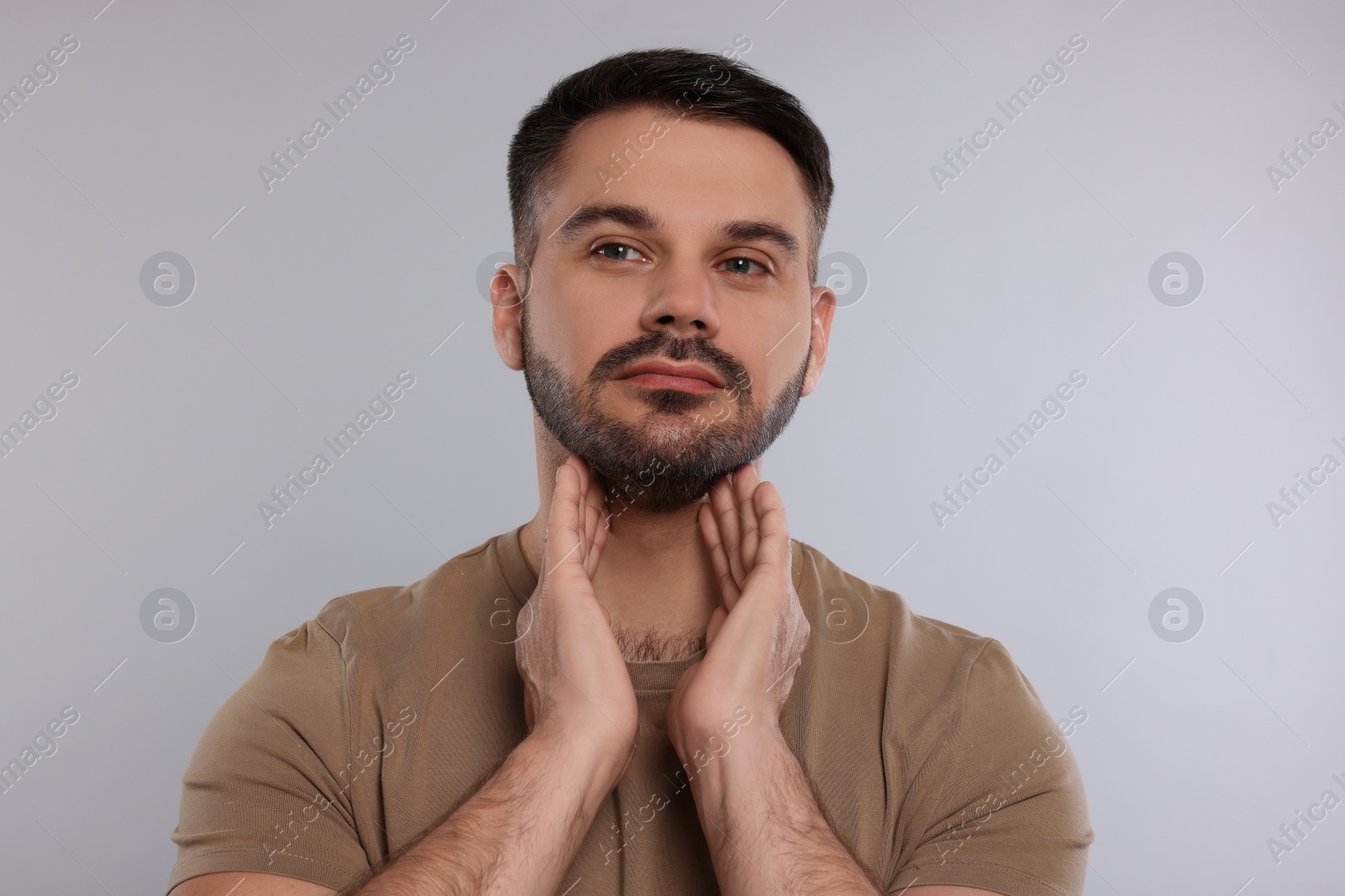 Photo of Endocrine system. Man doing thyroid self examination on light grey background