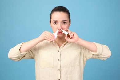 Photo of Woman using nasal sprays on light blue background