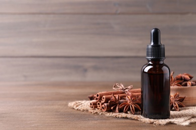 Photo of Anise essential oil and spices on wooden table, space for text