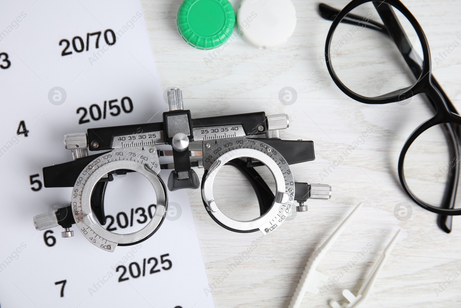 Photo of Different ophthalmologist tools on white wooden background, flat lay