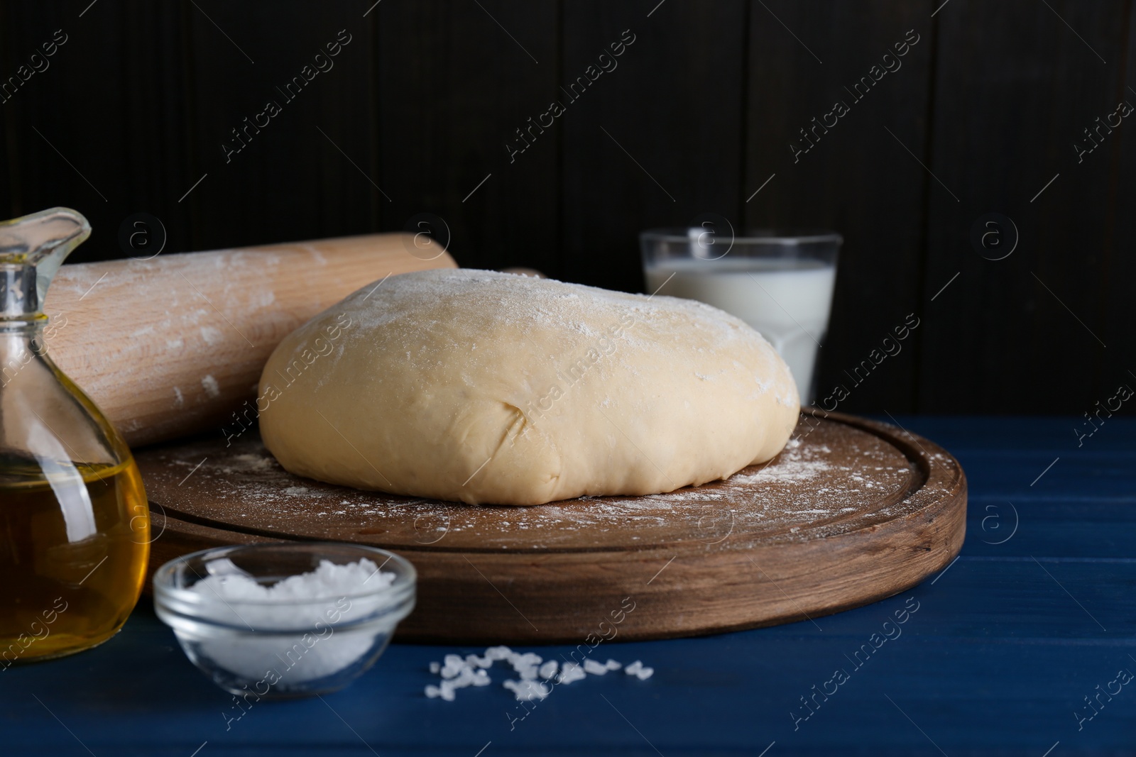 Photo of Fresh yeast dough and ingredients on blue wooden table