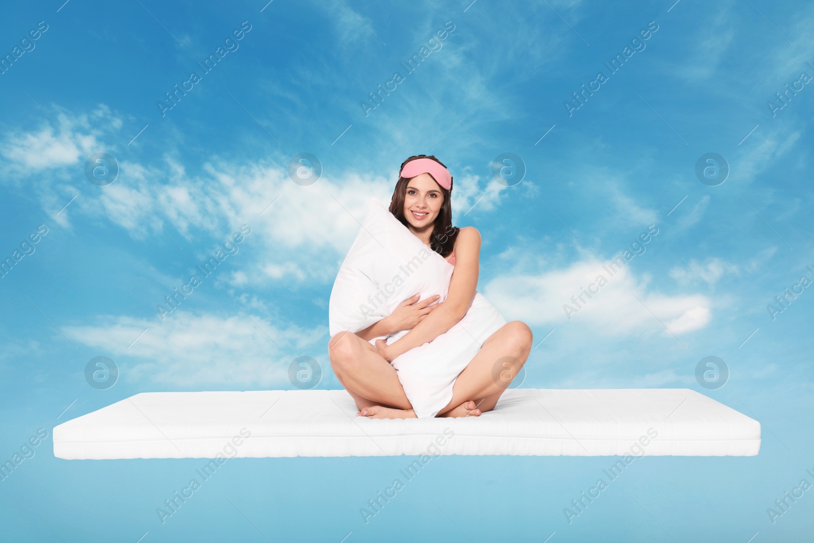 Image of Healthy sleep. Young woman with pillow on comfortable mattress in blue sky