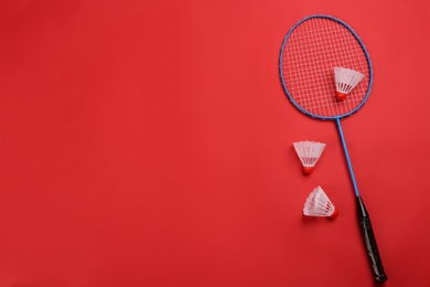 Photo of Racket and shuttlecocks on red background, flat lay with space for text. Badminton equipment