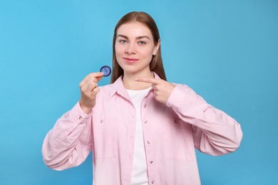 Photo of Woman holding condom on turquoise background. Safe sex
