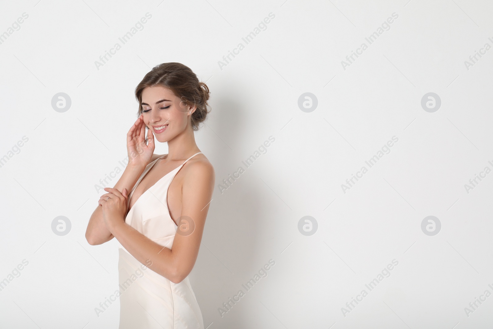 Photo of Young bride wearing beautiful wedding dress on light background. Space for text