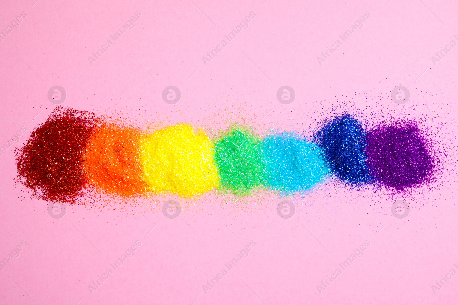 Photo of Bright glitters on pink background, flat lay. Rainbow colors