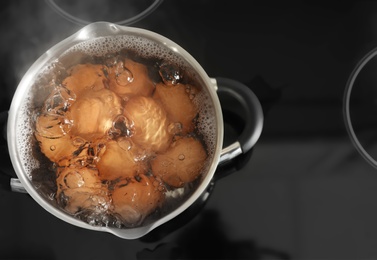 Cooking chicken eggs in pot on electric stove, top view. Space for text