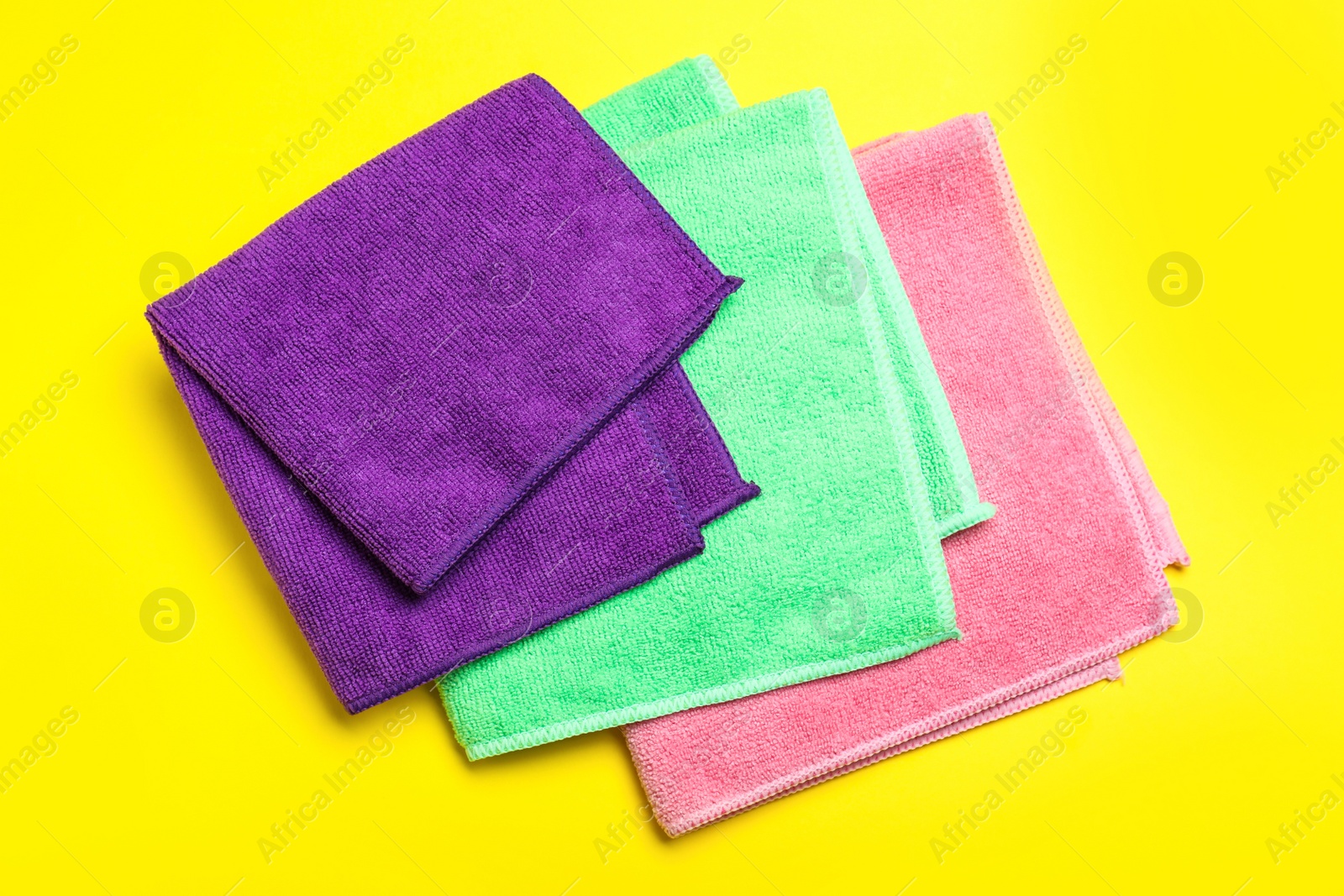 Photo of Colorful microfiber cloths on yellow background, flat lay