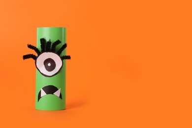 Photo of Funny green monster on orange background, space for text. Halloween decoration