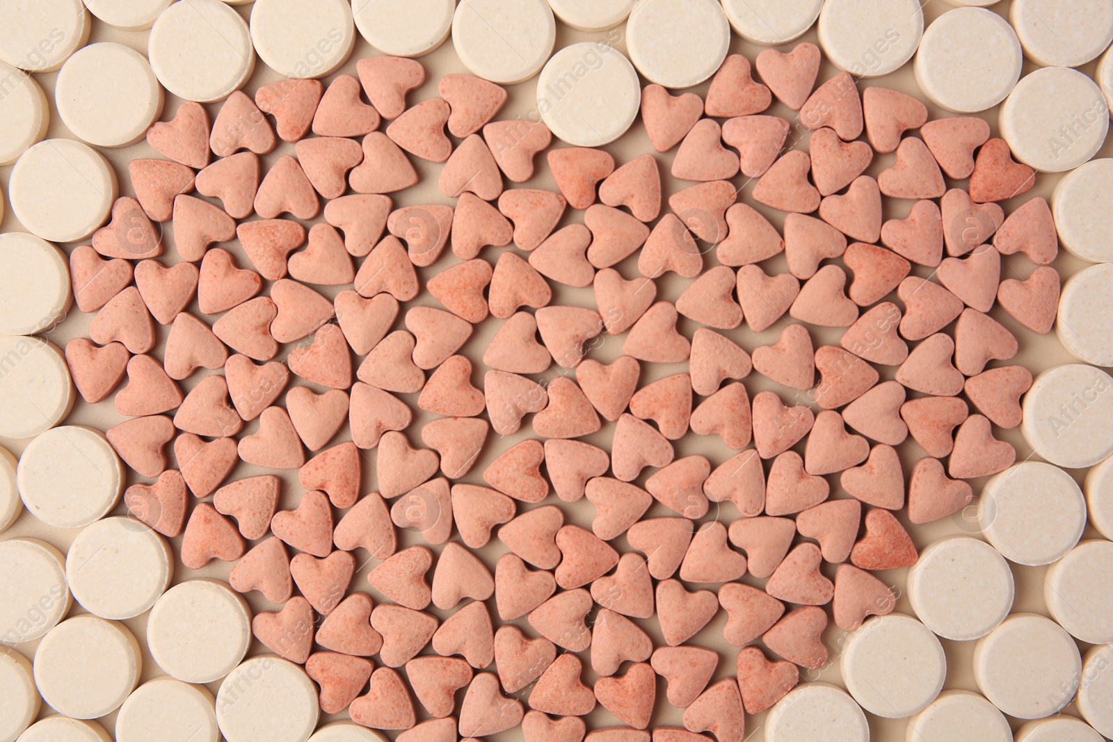 Photo of Heart made of vitamins for pets on beige background, flat lay