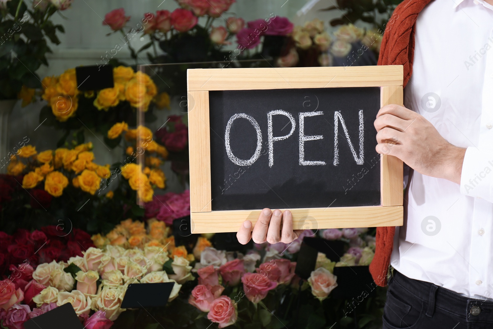 Photo of Male business owner holding OPEN sign in his flower shop, closeup