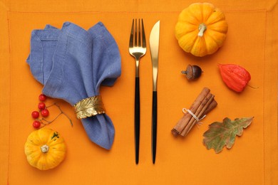 Photo of Flat lay composition with cutlery and napkin on orange tablecloth. Table setting