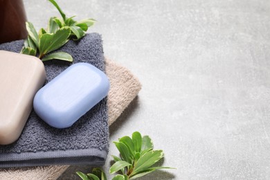 Photo of Soap bars and terry towels on light grey table. Space for text