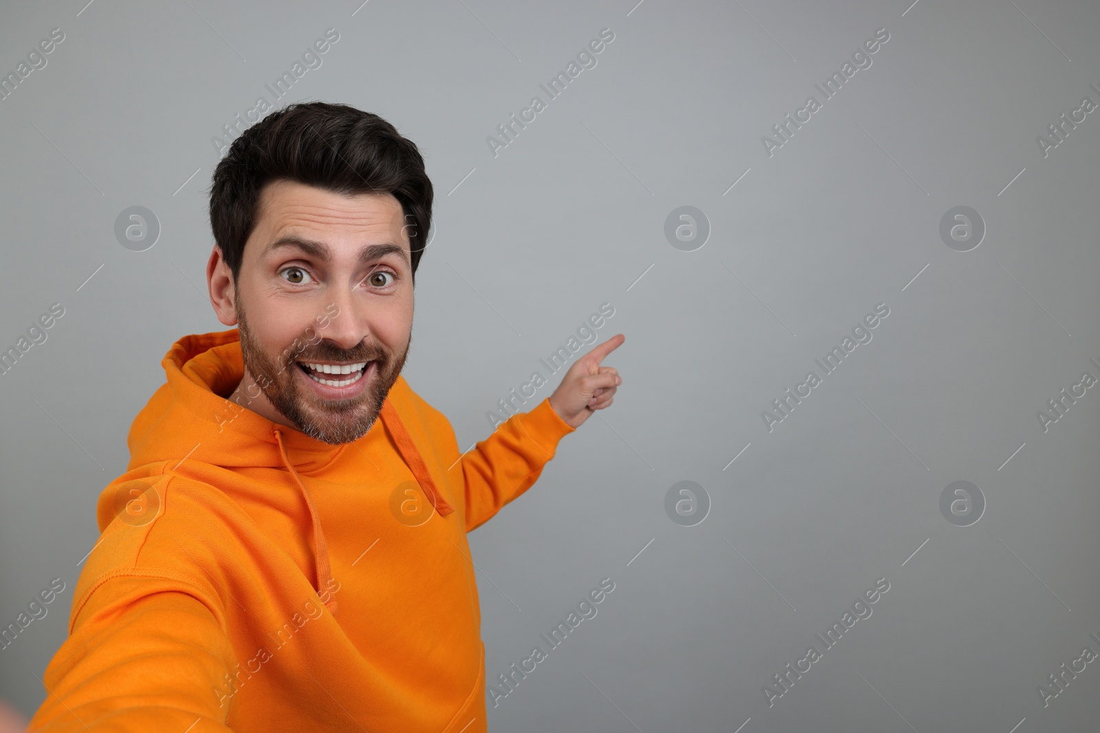 Photo of Smiling man taking selfie on grey background, space for text