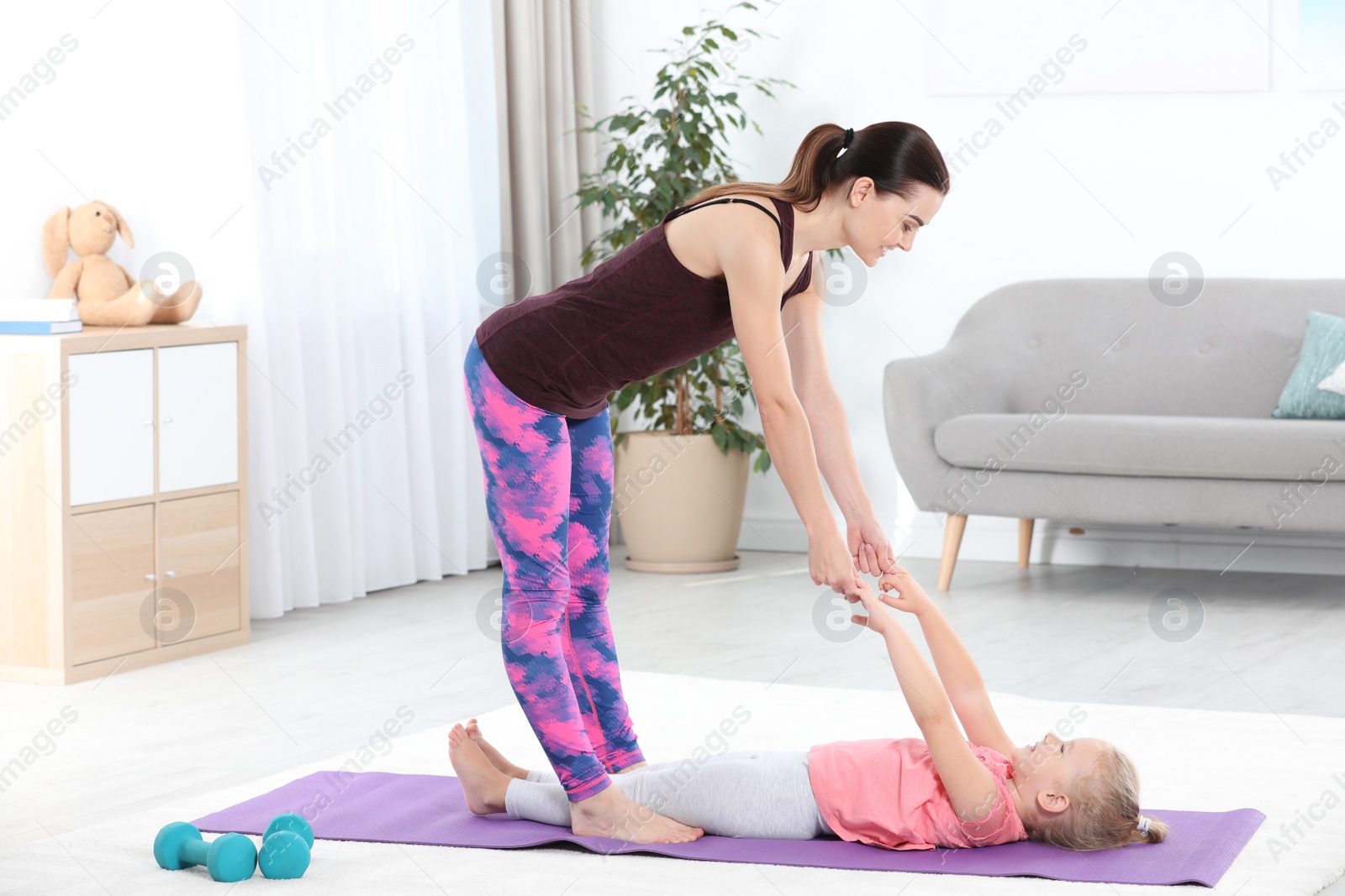 Photo of Sportive woman doing fitness exercises with daughter at home