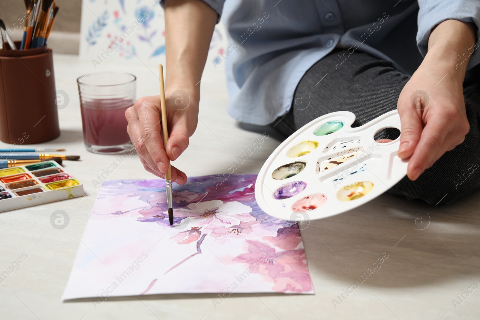 Photo of Woman painting flowers with watercolor on floor, closeup