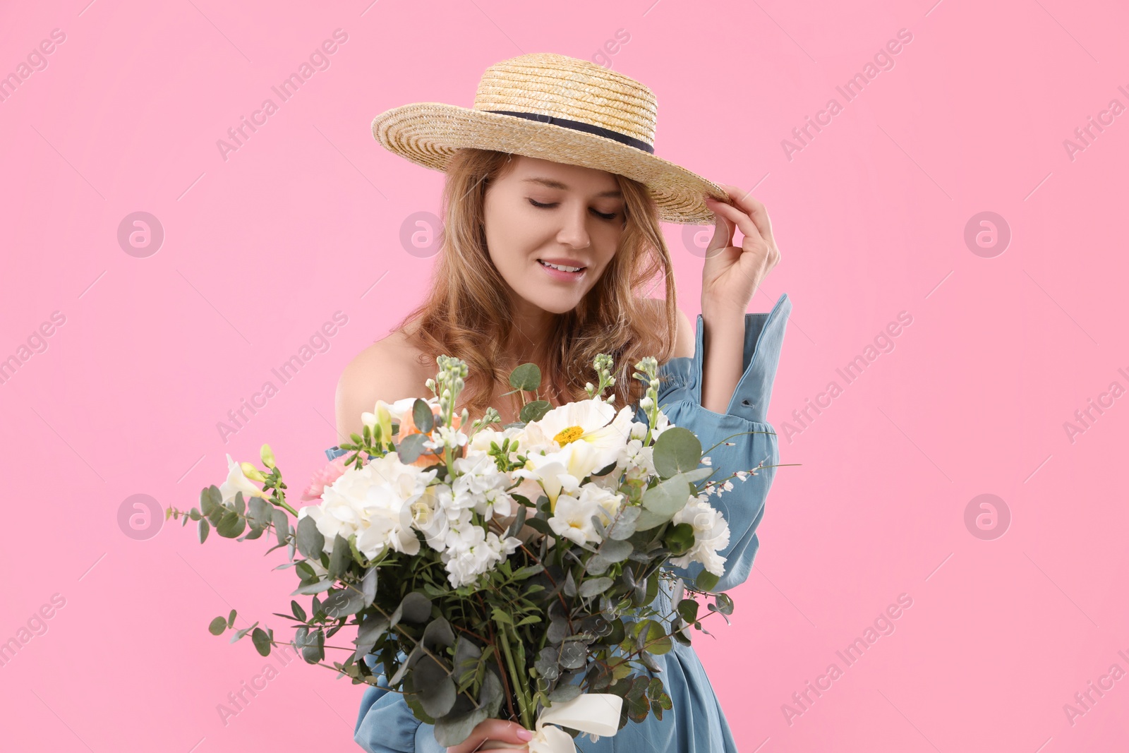 Photo of Beautiful woman in straw hat with bouquet of flowers on pink background