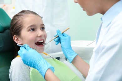Photo of Professional dentist working with little patient in modern clinic