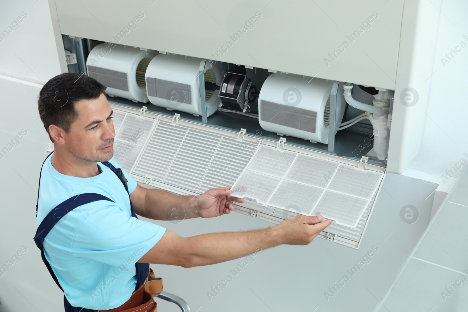 Photo of Male technician cleaning air conditioner indoors