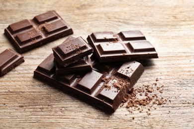 Photo of Pieces of tasty chocolate on wooden background