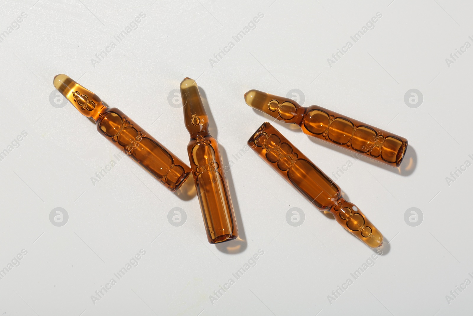 Photo of Glass ampoules with liquid on white background, top view