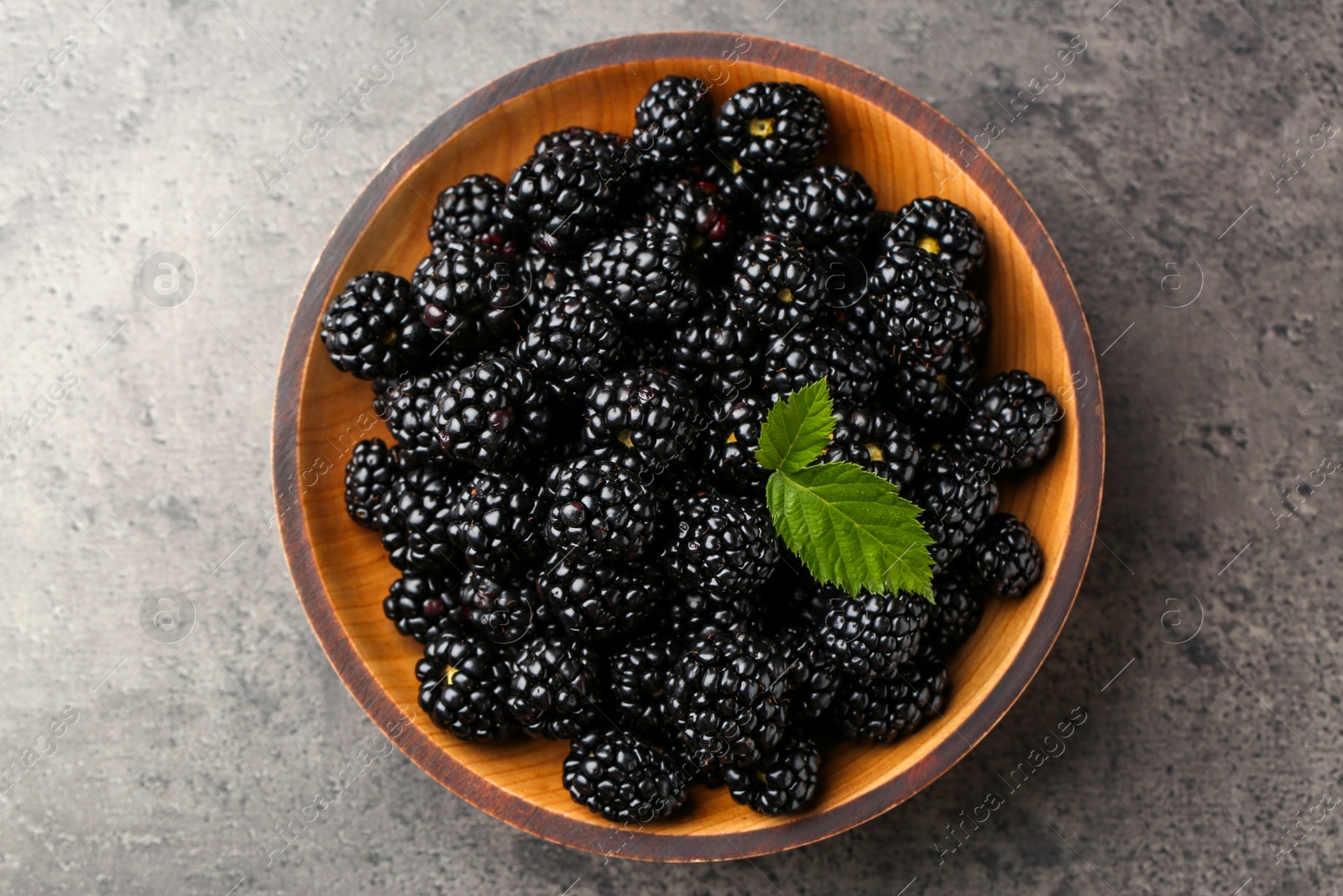 Photo of Bowl with fresh ripe blackberries on dark grey table, top view