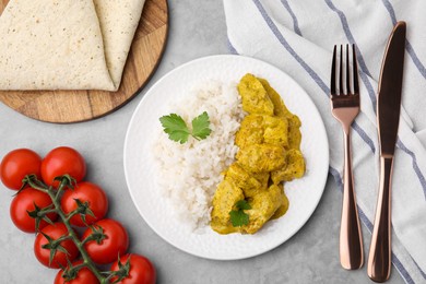 Photo of Delicious rice, chicken with curry sauce and tomatoes on light grey table, flat lay