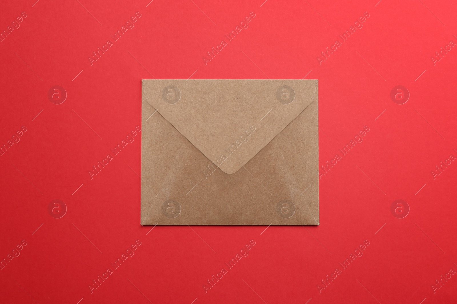 Photo of Brown paper envelope on red background, top view