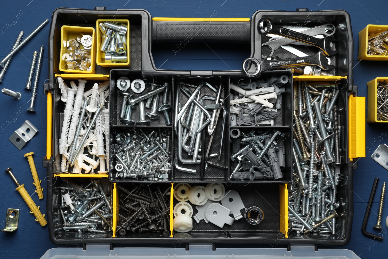 Photo of Organizer with many different fasteners and wrenches on blue wooden table, flat lay