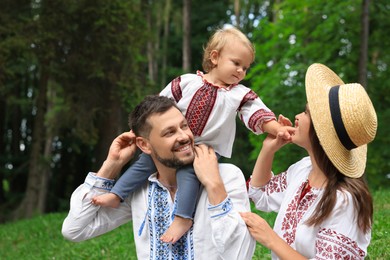 Photo of Happy family in Ukrainian national clothes outdoors