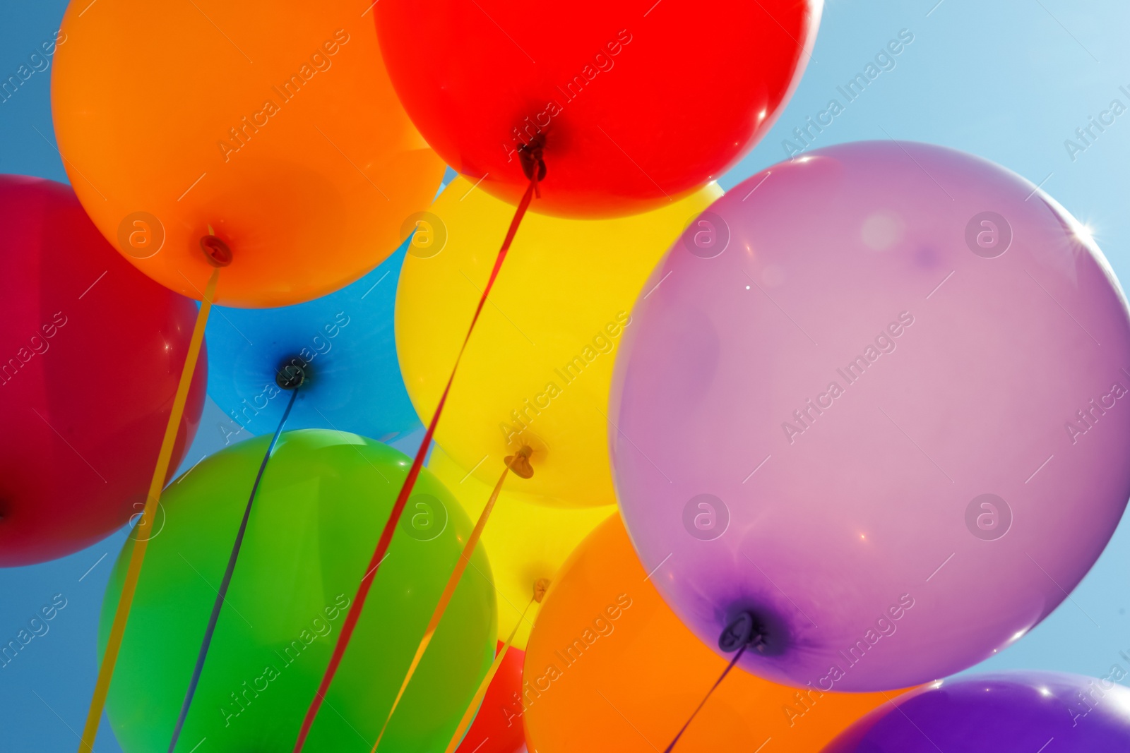 Photo of Bright colorful balloons with ribbons, closeup view