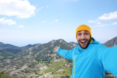 Image of Smiling young man taking selfie in mountains