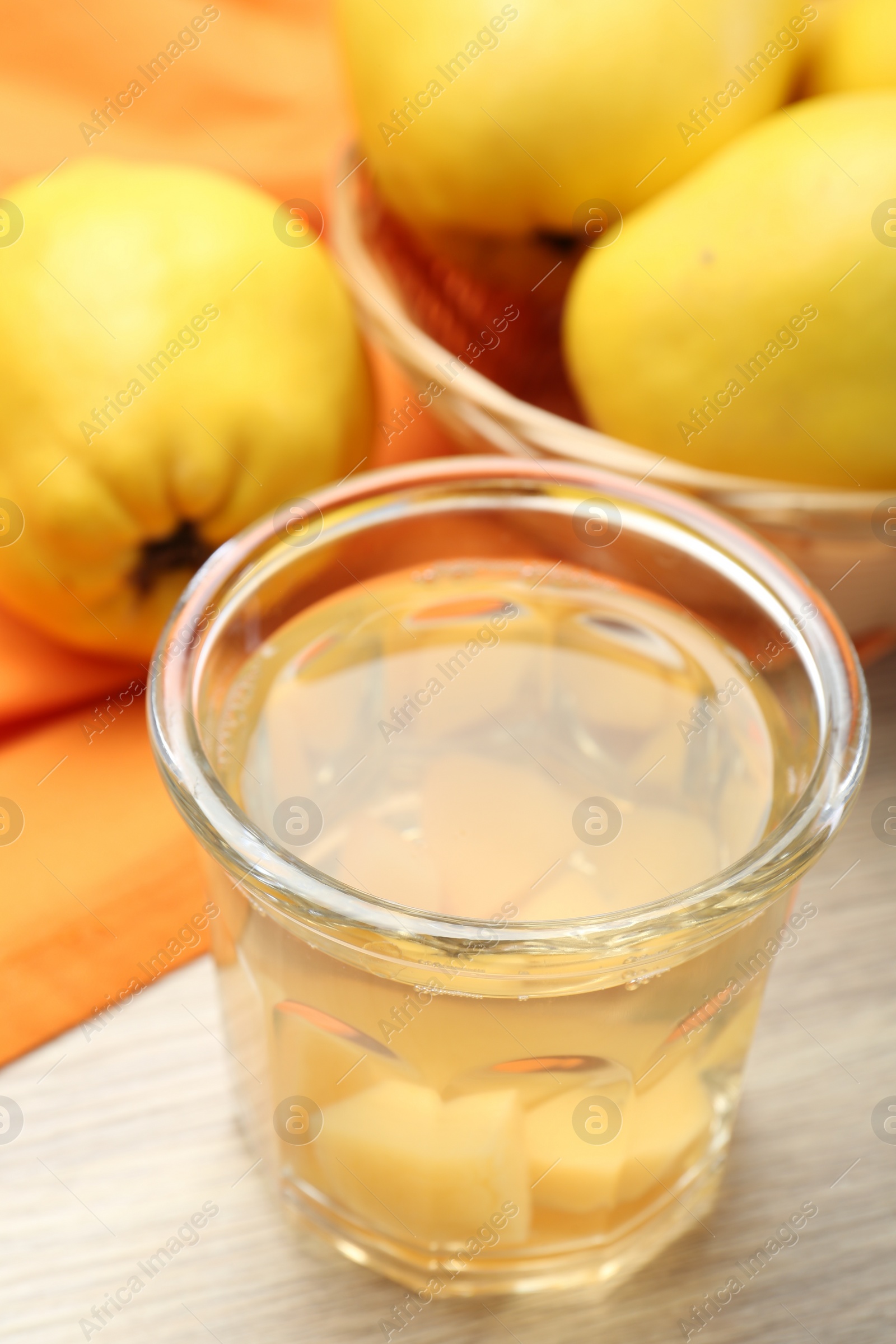 Photo of Delicious quince drink in glass and fresh fruits on wooden table, closeup