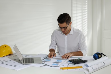 Photo of Architect working with construction drawings in office