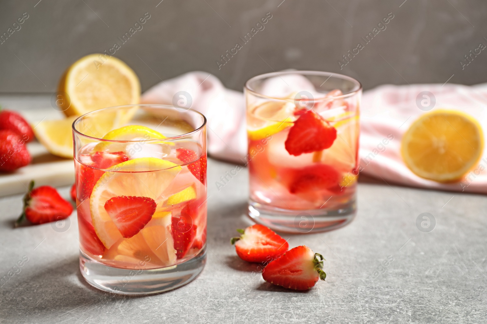 Photo of Tasty refreshing drink with strawberries and lemon on light grey table