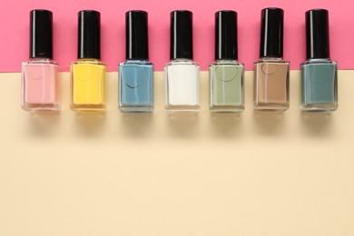 Beautiful nail polishes in bottles on color background, flat lay. Space for text