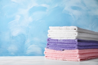 Stack of soft bath towels on table. Space for text