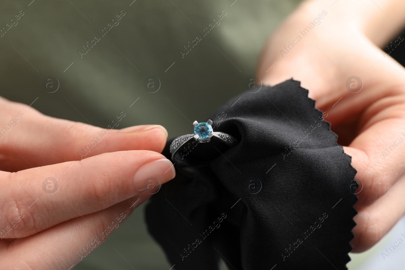 Photo of Jeweler cleaning topaz ring with microfiber cloth, closeup